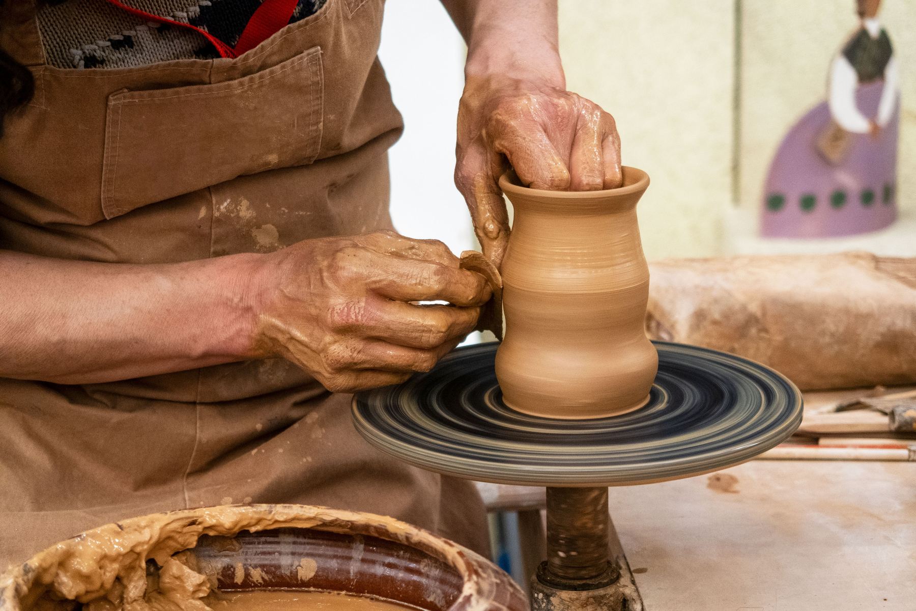 Hands shaping wet clay in the sunlit studio at SuperHuman